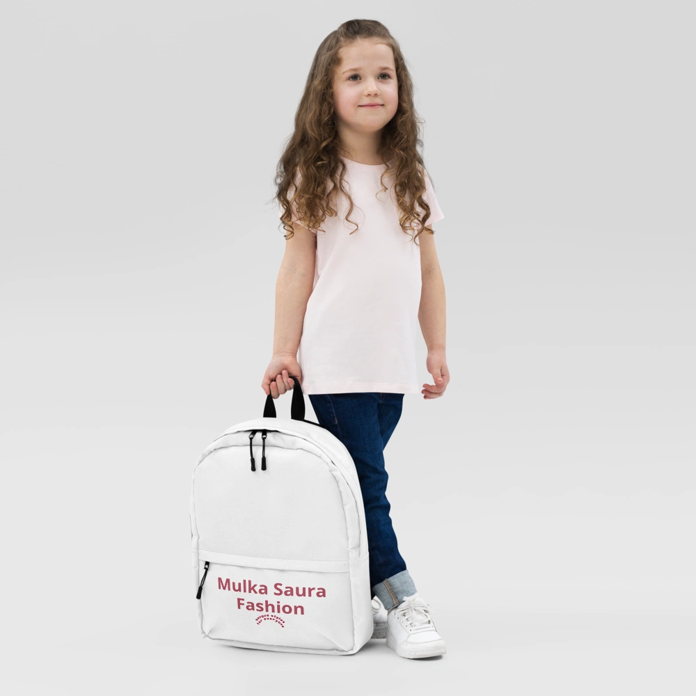 Child holding a white backpack, smiling.