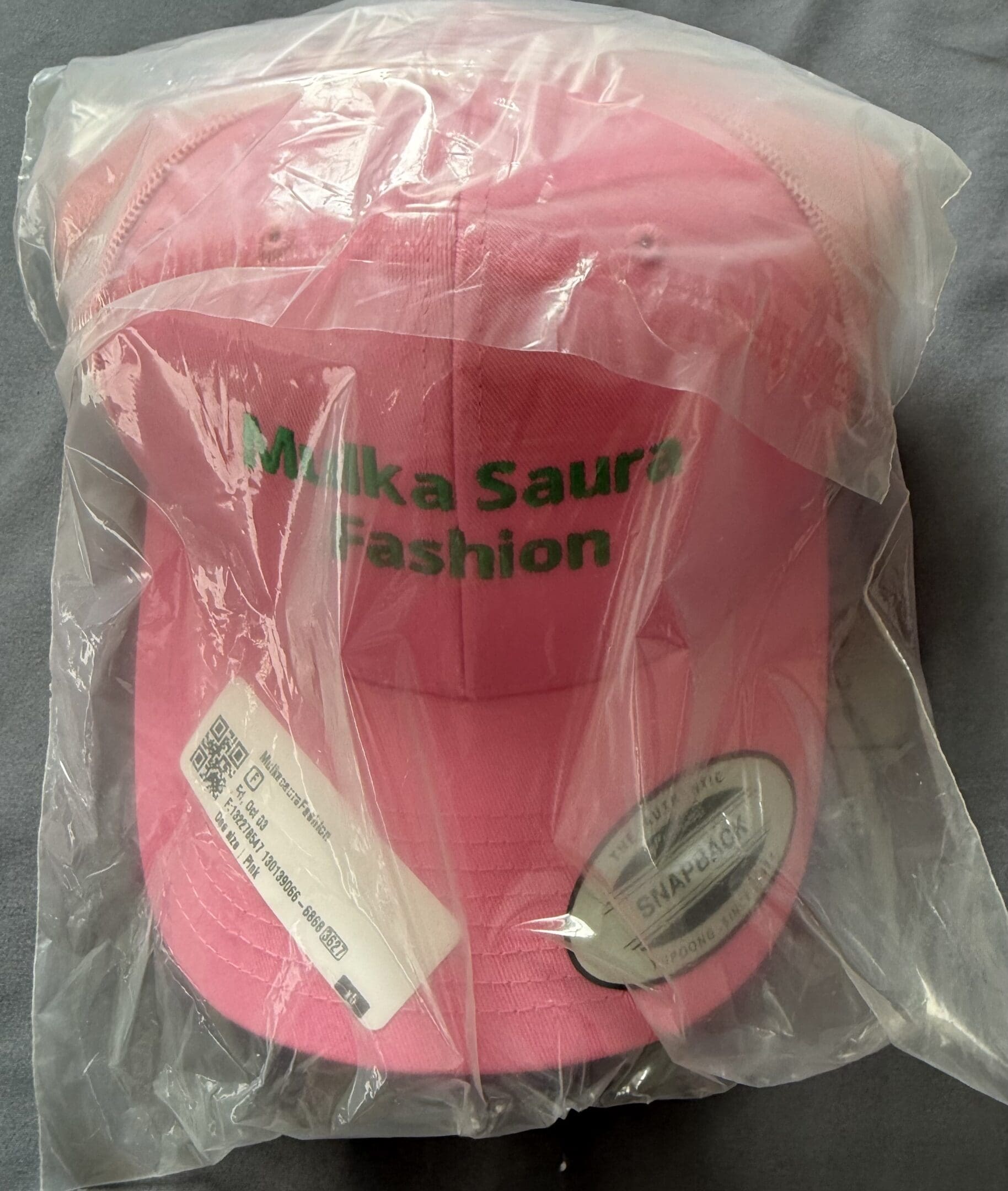 Pink cap with green text, packaged.