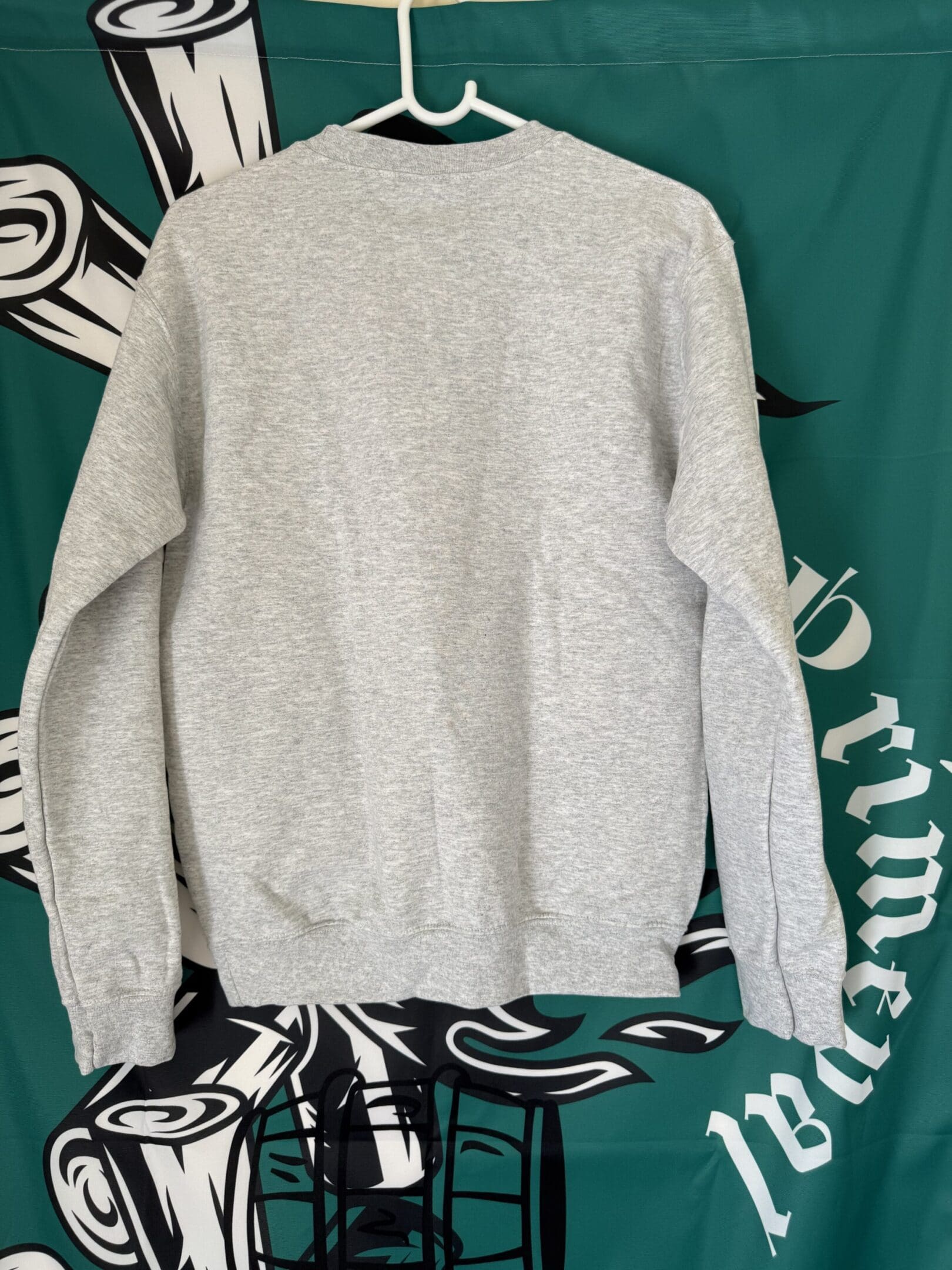 Gray sweatshirt on hanger, green background.