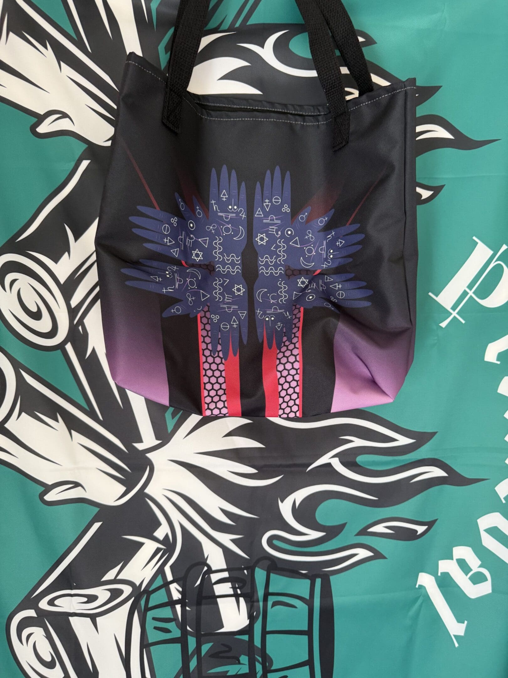 Black tote bag with abstract colorful design.