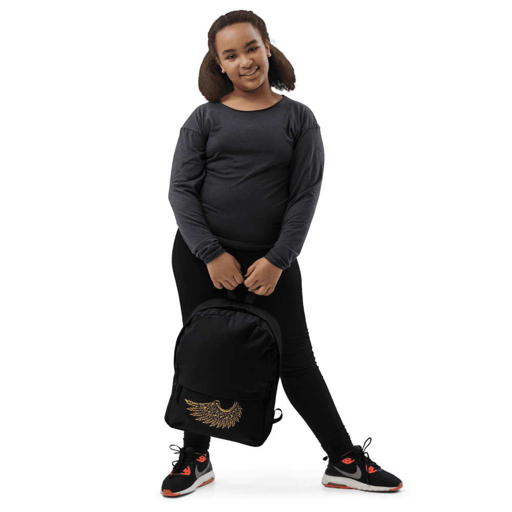 Girl smiling, holding a black backpack.