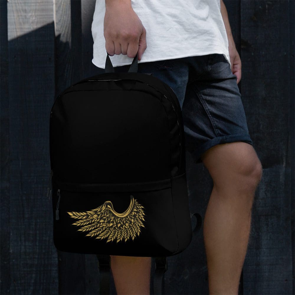 Person holding black backpack with golden wings.