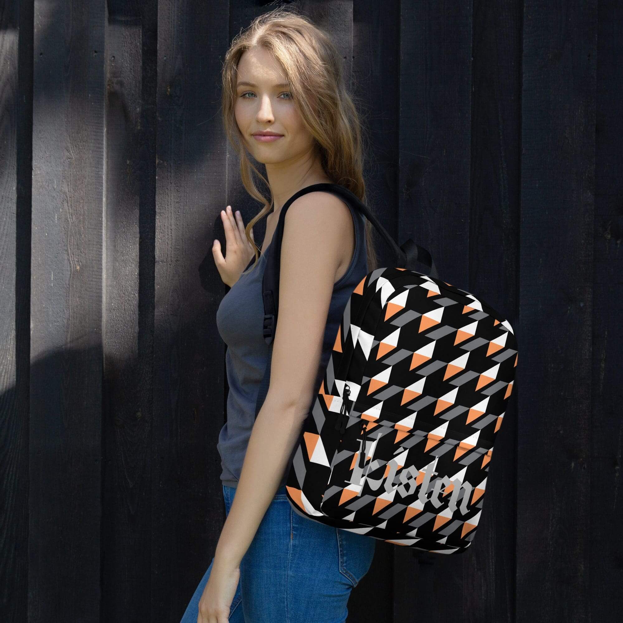 Woman with patterned backpack against dark wall.