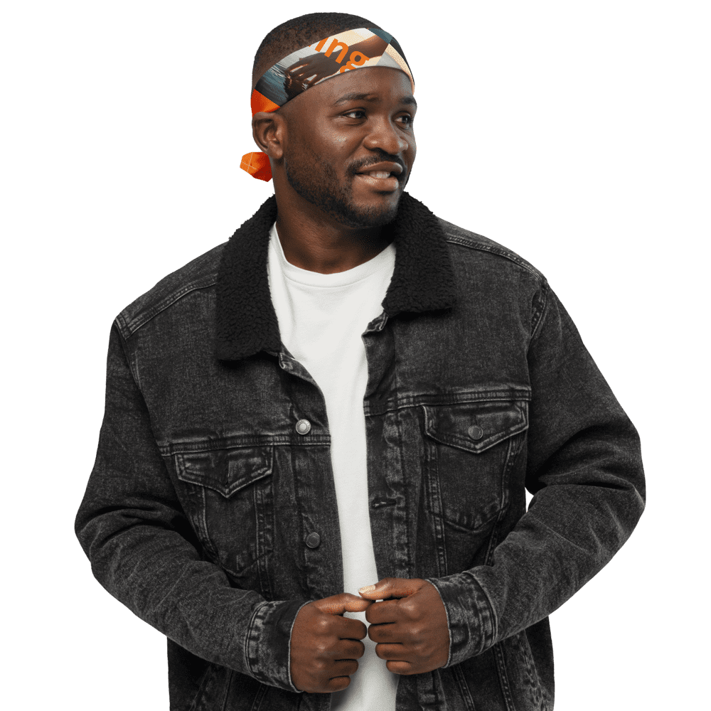 Man in denim jacket, orange headband smiling.