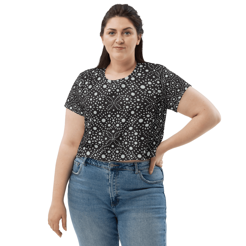 Woman in patterned shirt and jeans smiling.
