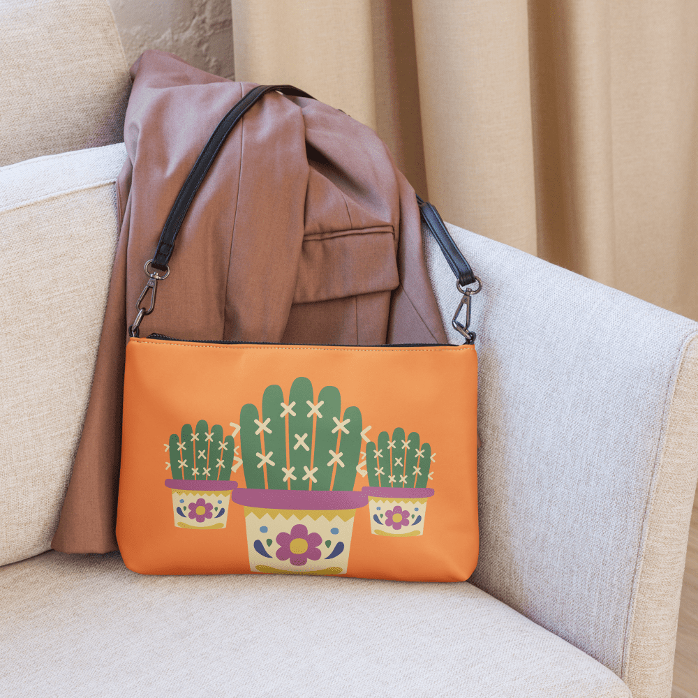 Orange cactus-themed purse on beige chair.