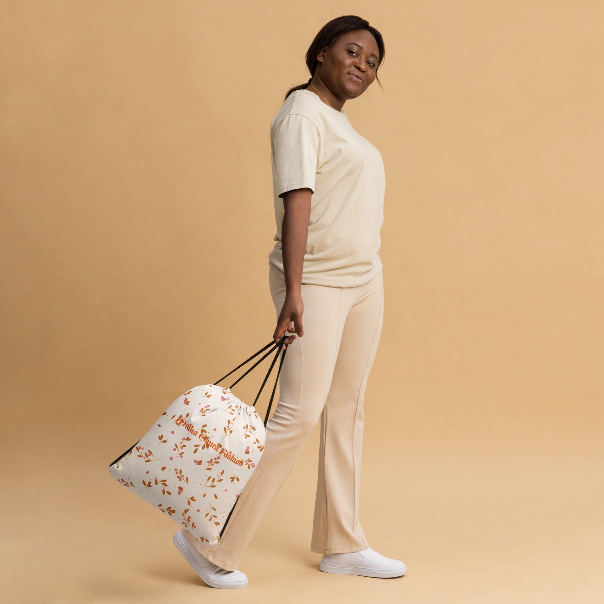 Woman in beige outfit holding floral bag.