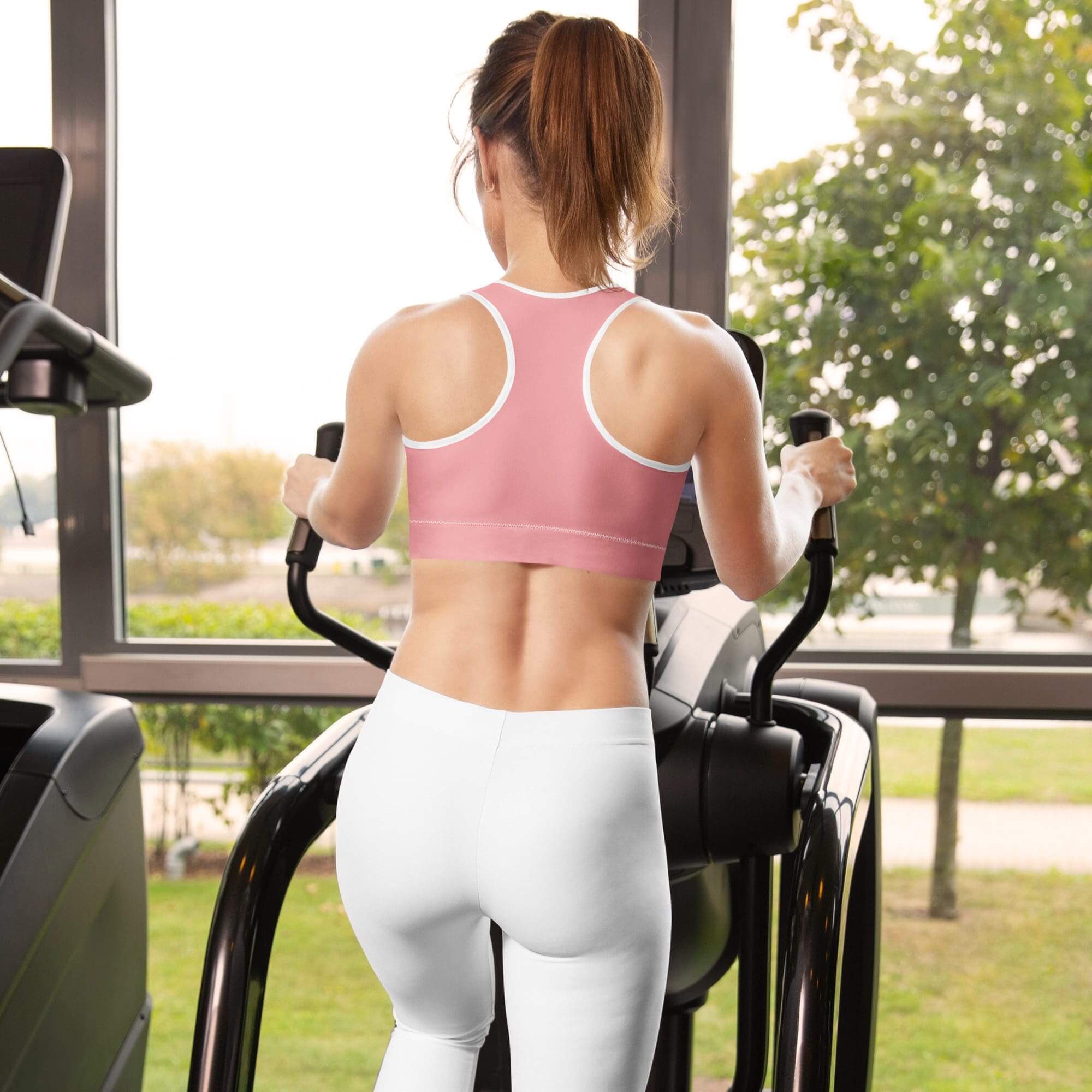 Woman exercising on elliptical trainer by window