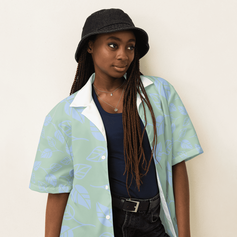 Woman wearing a hat and leaf-patterned shirt.