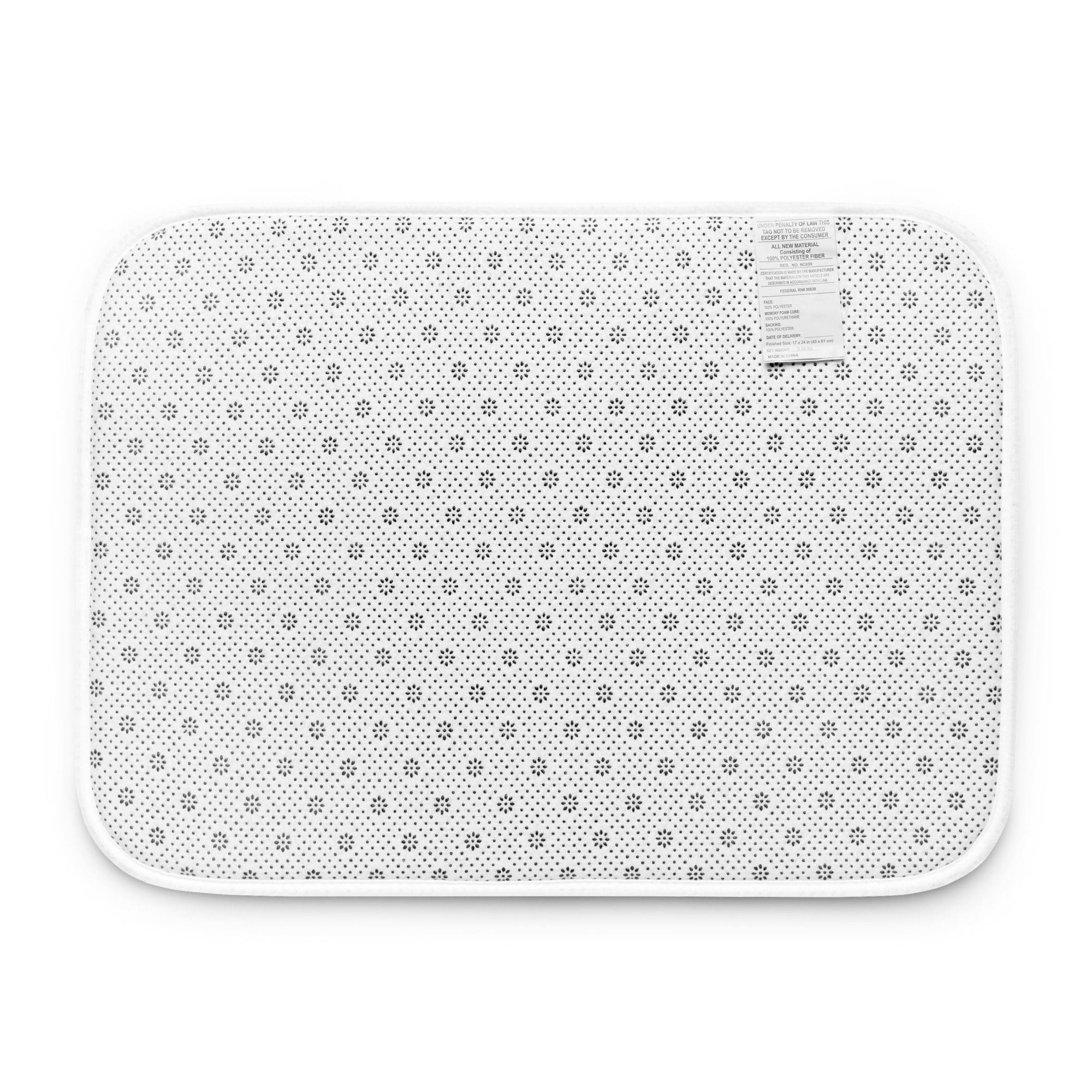 White bath mat with small black flowers.