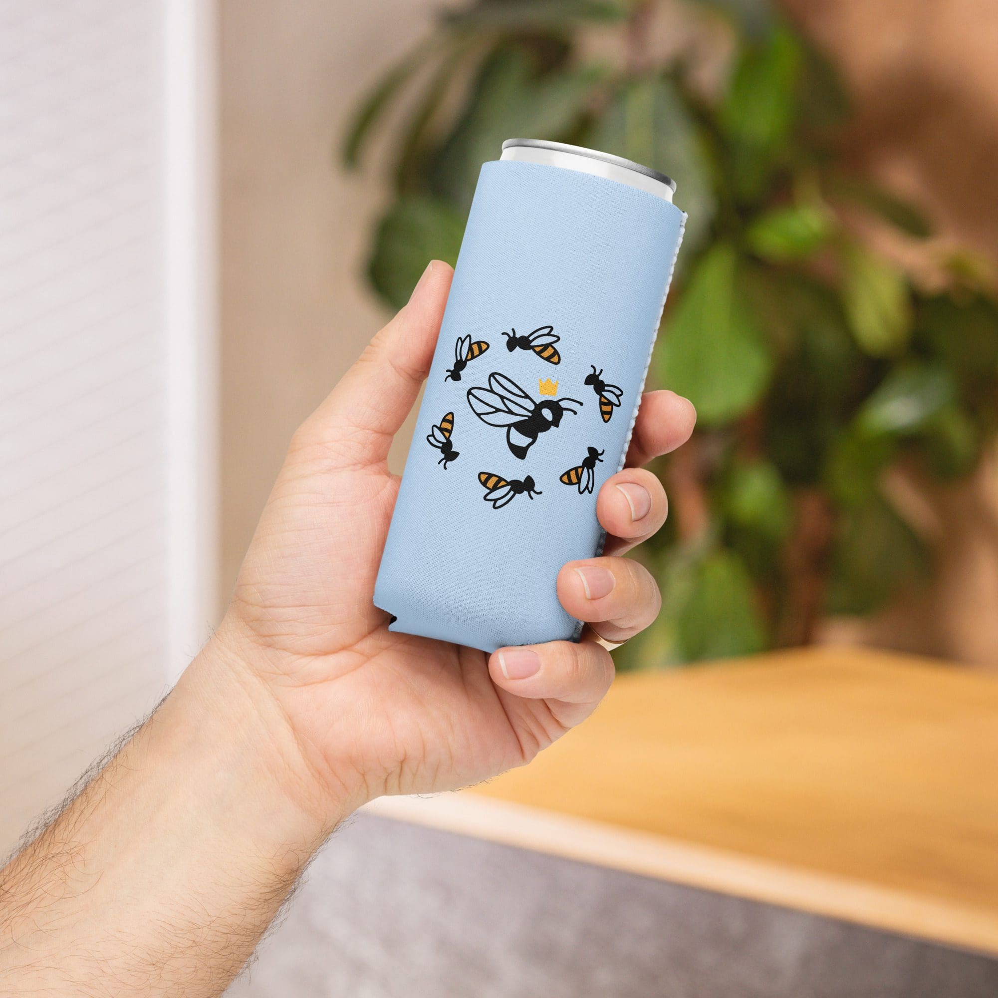 Hand holding bee-patterned can sleeve.