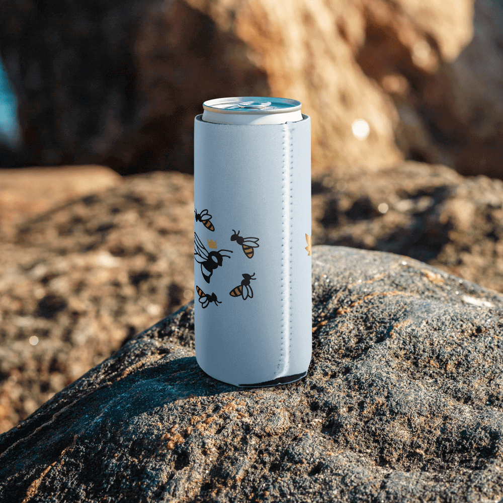 Bee-patterned can cooler on rocky surface.