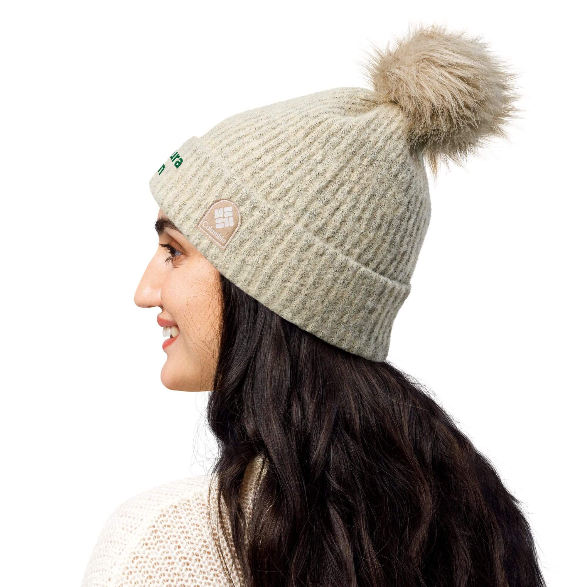 Smiling woman in beige knit pom-pom beanie