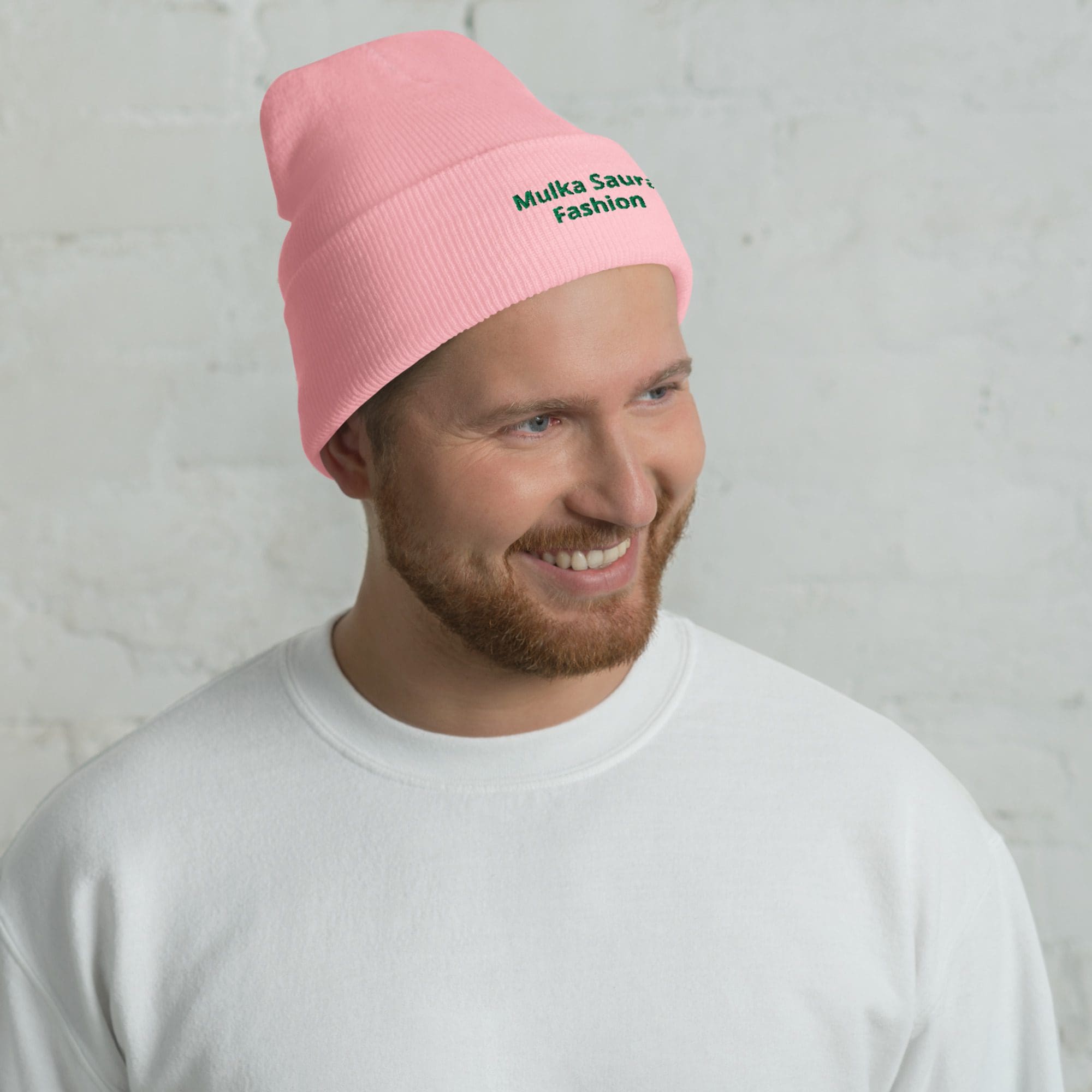 Smiling man wearing pink beanie hat.