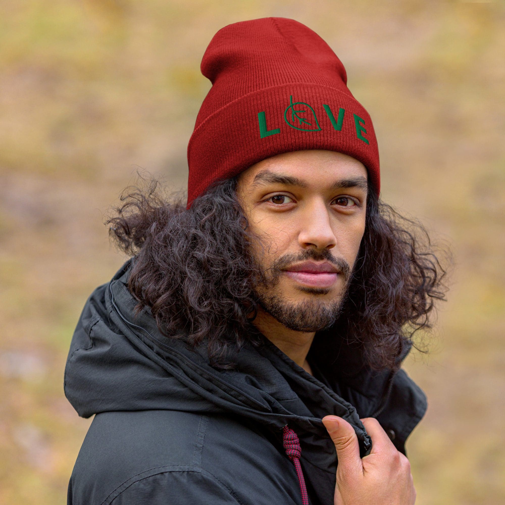 Man wearing red hat outdoors, looking serious.