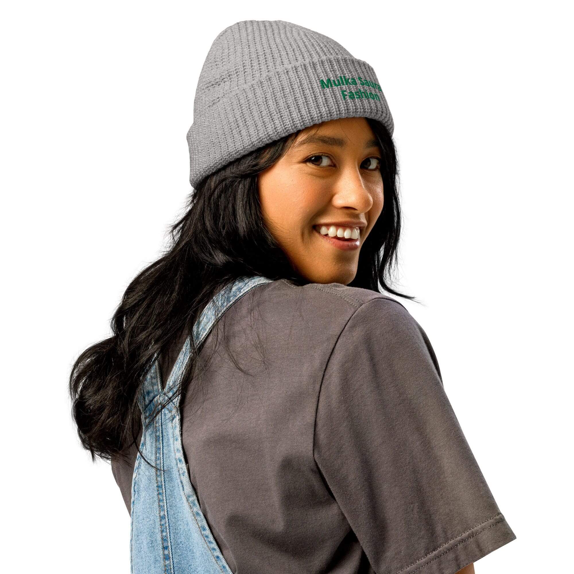 Woman smiling, wearing gray beanie and overalls.