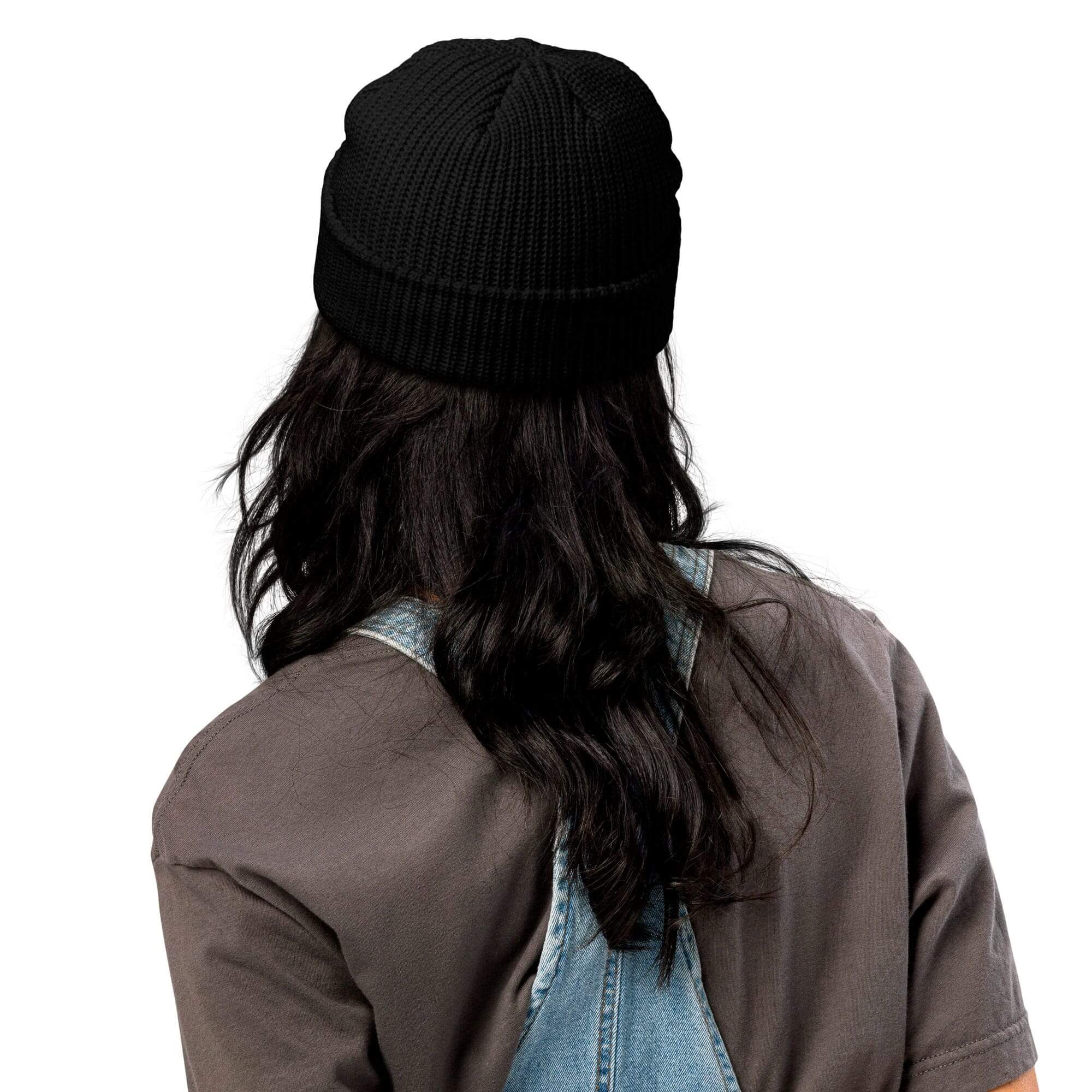 Person wearing black beanie and denim overalls.