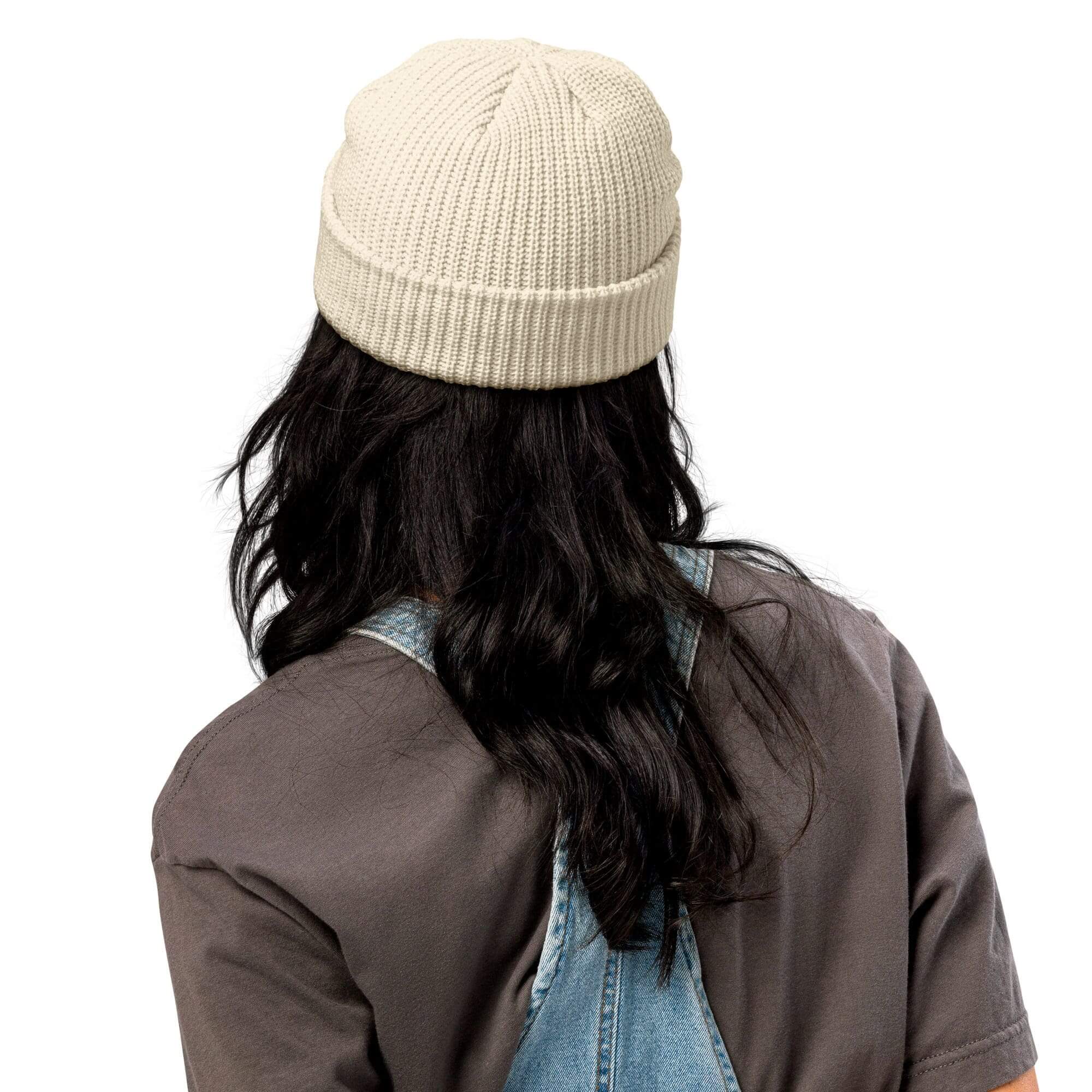 Person in beanie and overalls, back view.