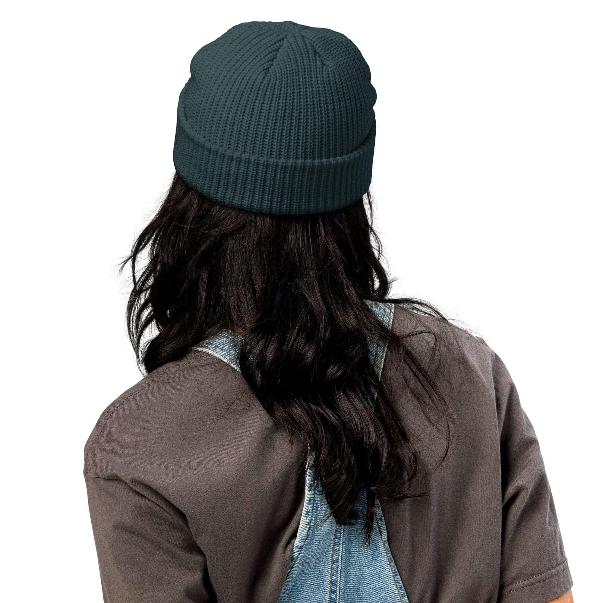 Person wearing black beanie and overalls, back.