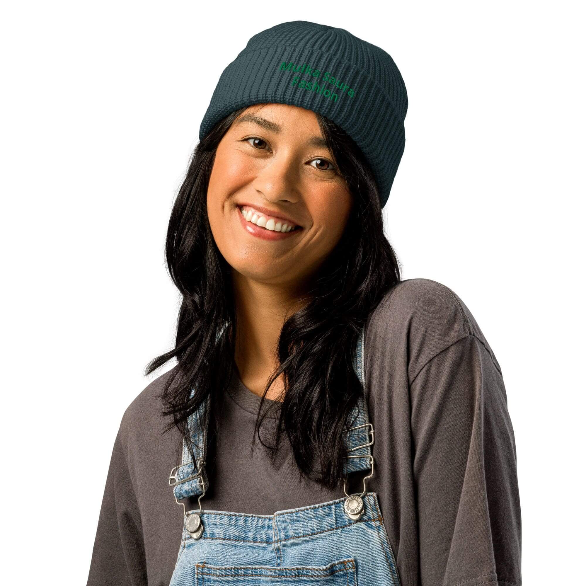 Woman in overalls and beanie smiling.