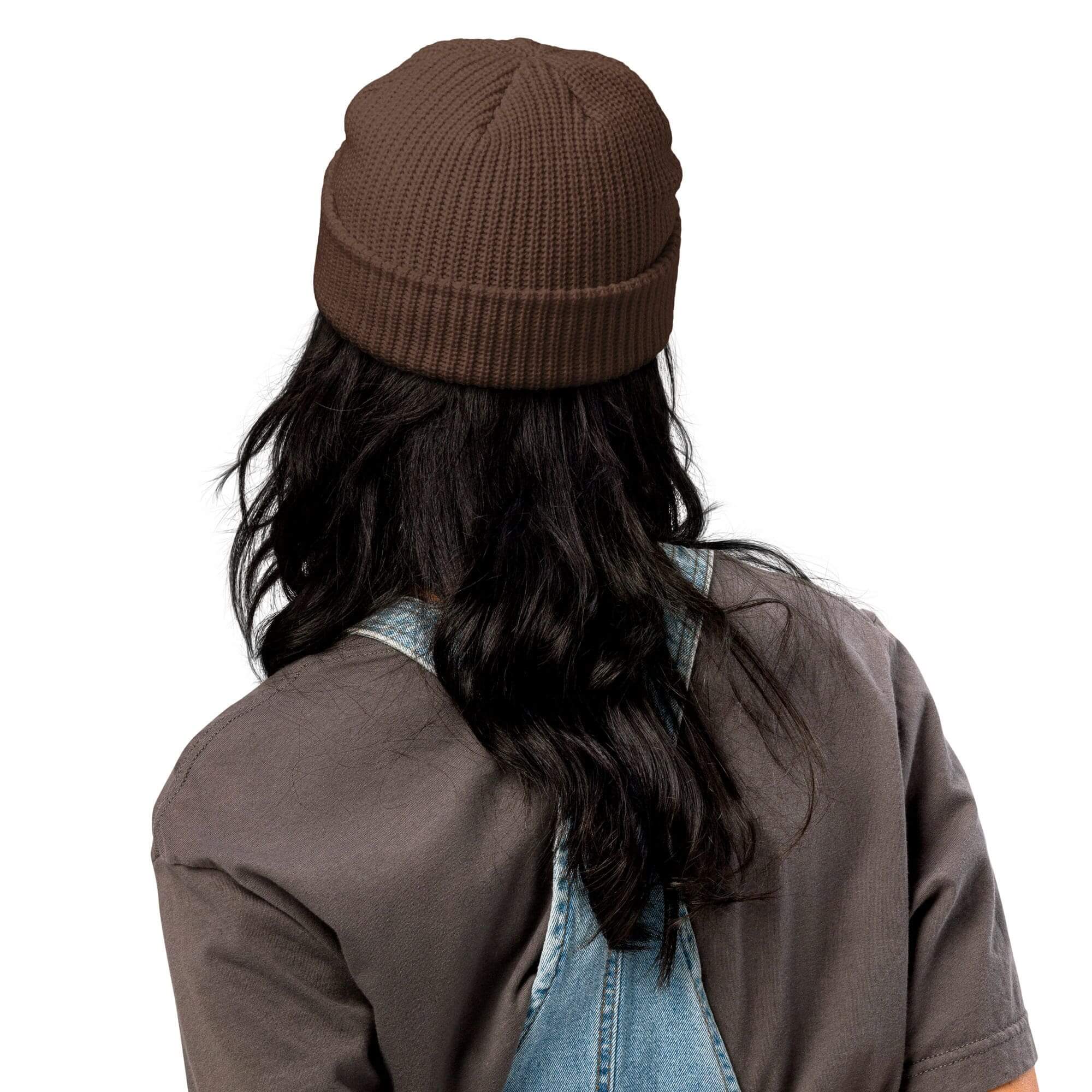 Person wearing beanie and denim overalls, back.