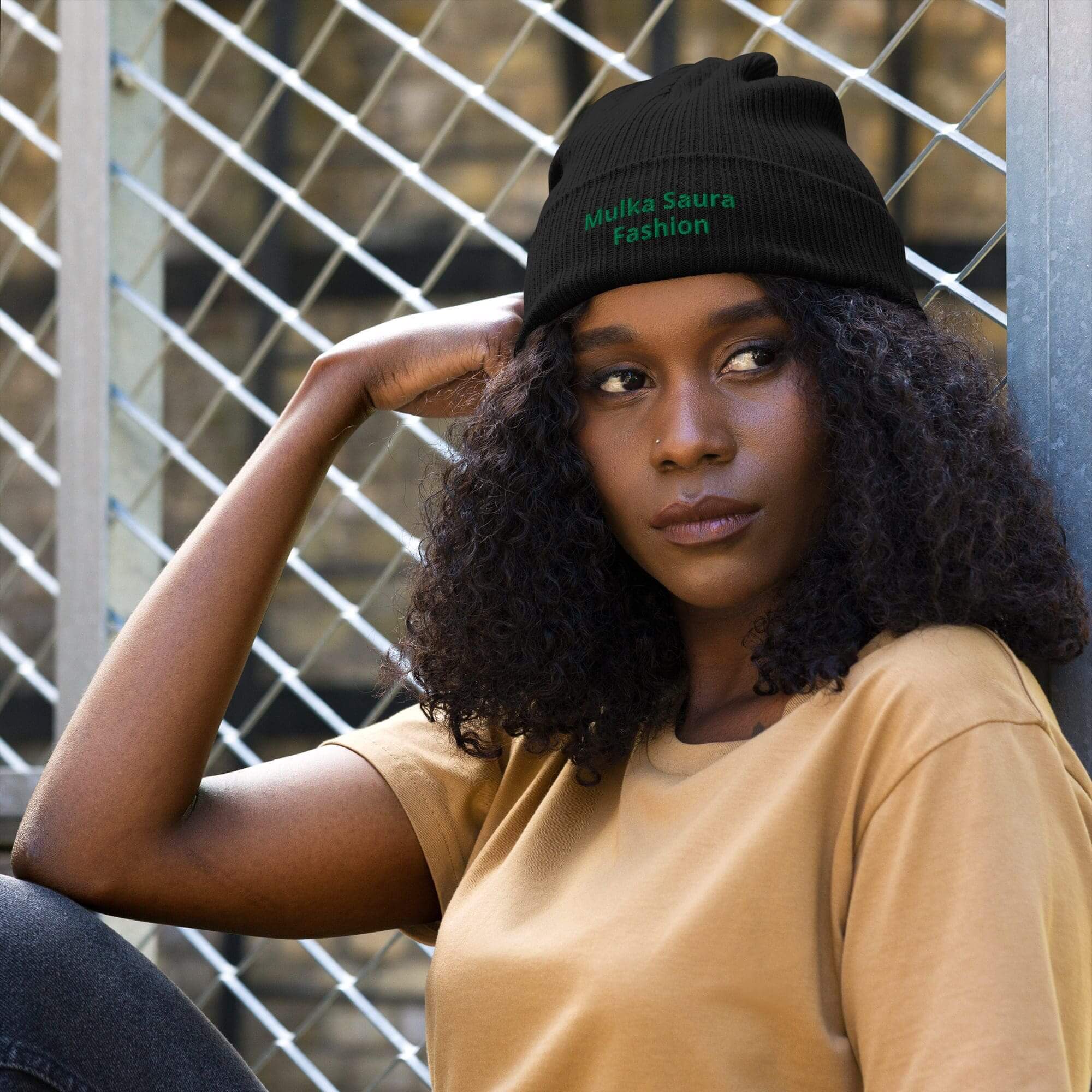 Woman wearing black beanie near chain-link fence.