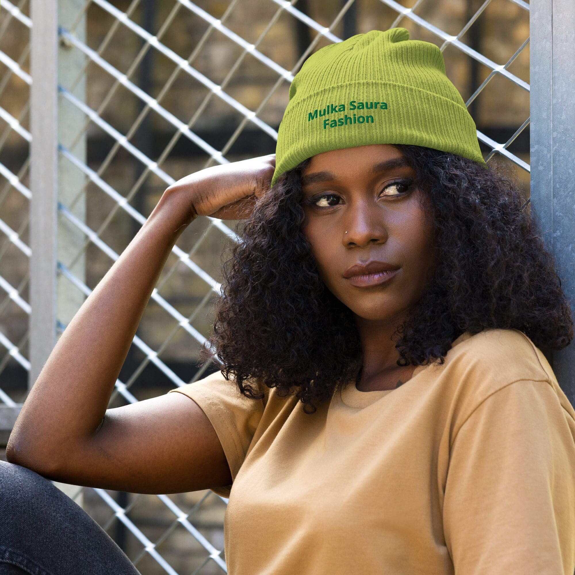 Woman wearing green beanie, leaning on arm.