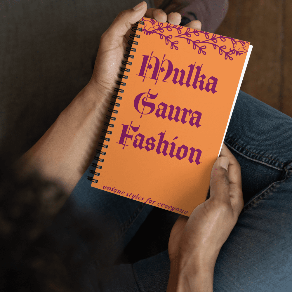 Person holding orange fashion notebook, sitting casually.