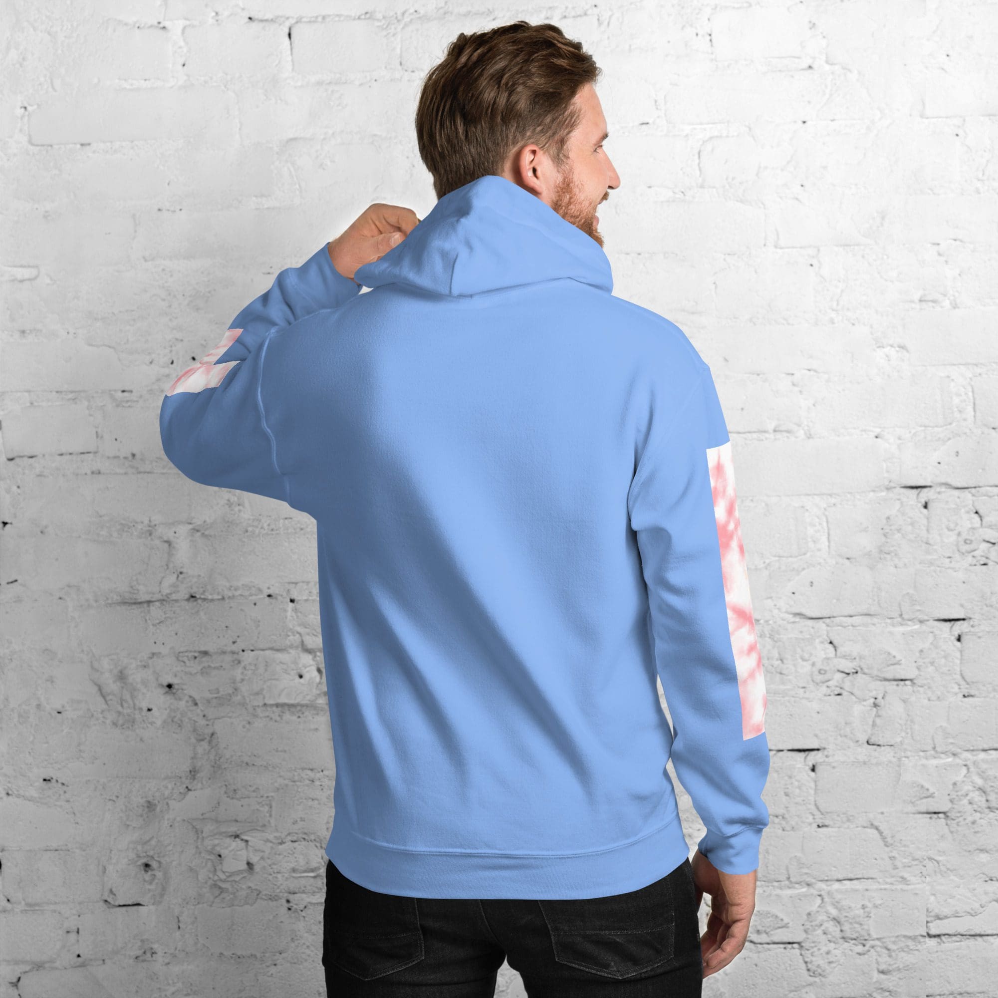 Man in blue hoodie facing brick wall.