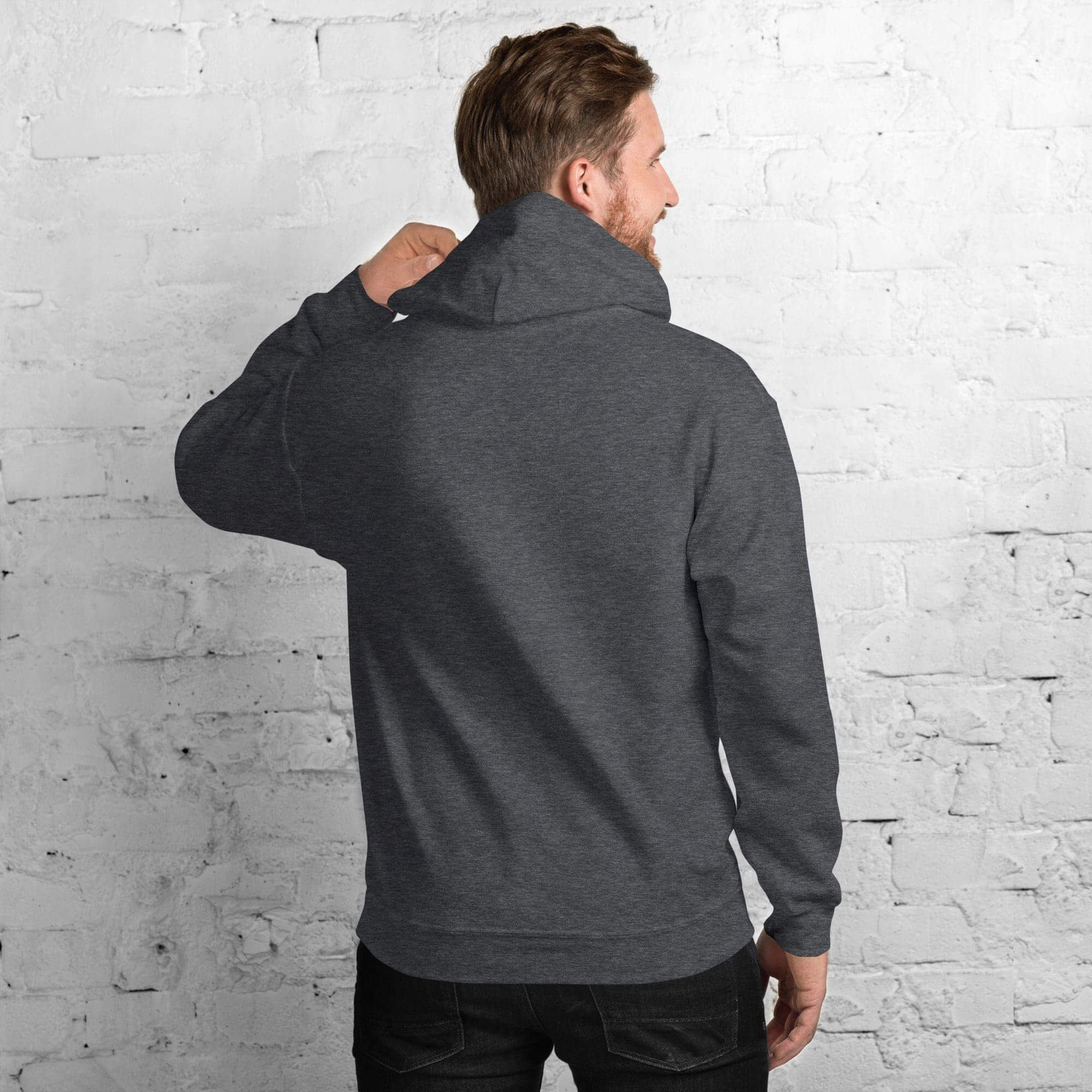 Man in hoodie facing white brick wall.