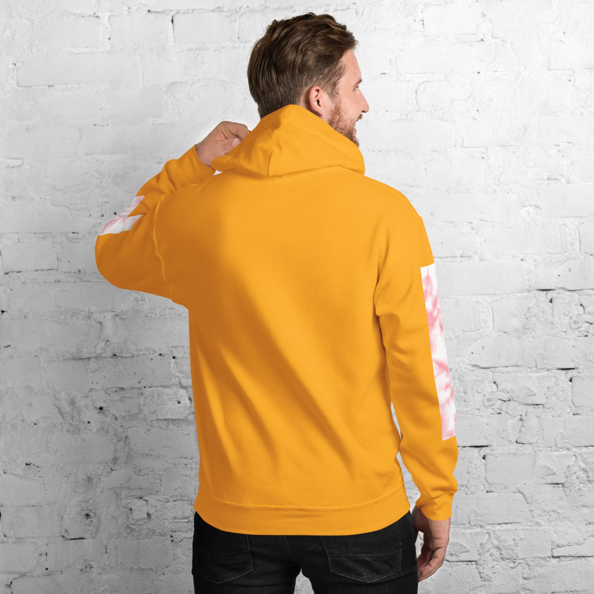 Man in orange hoodie facing wall.