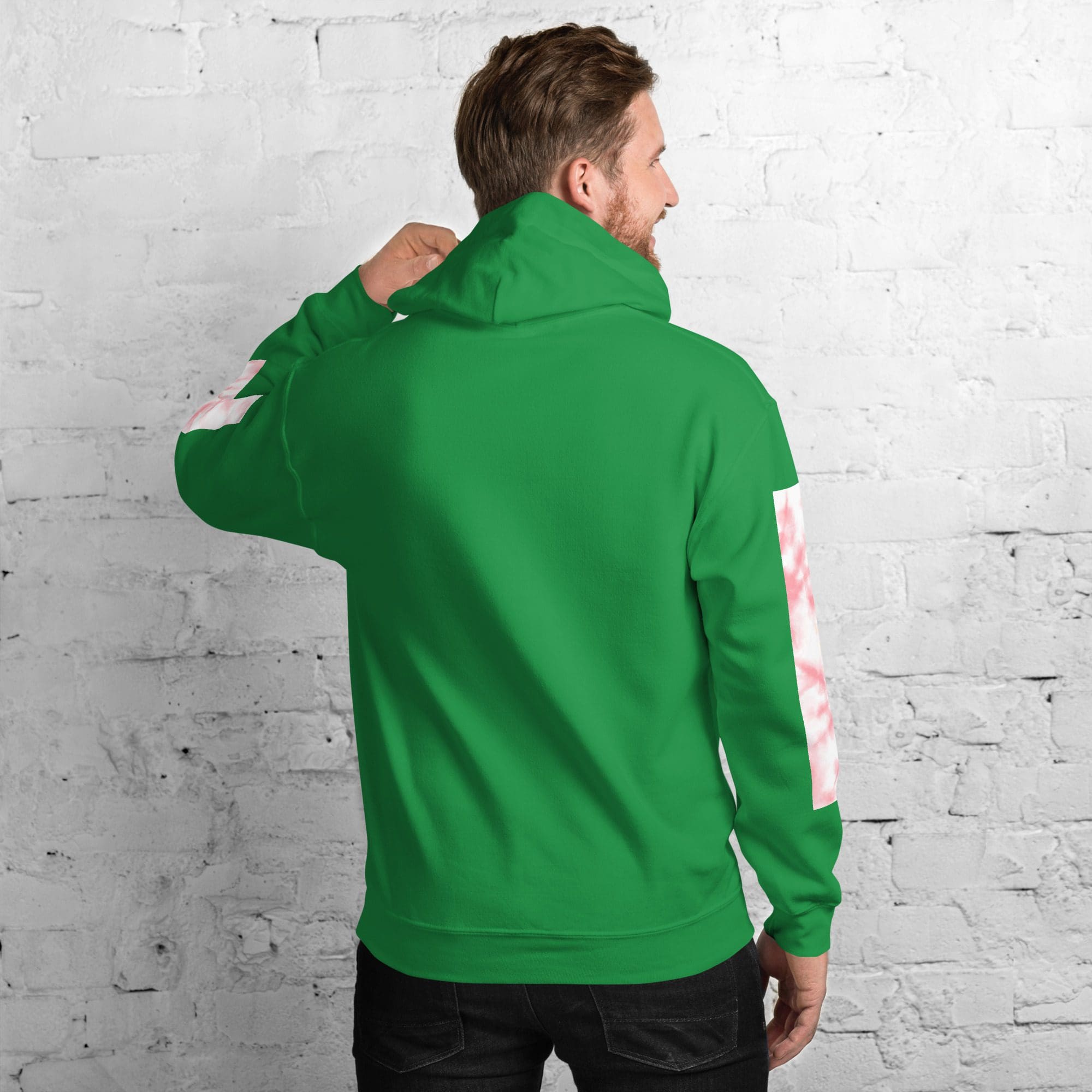 Man wearing green hoodie facing brick wall.