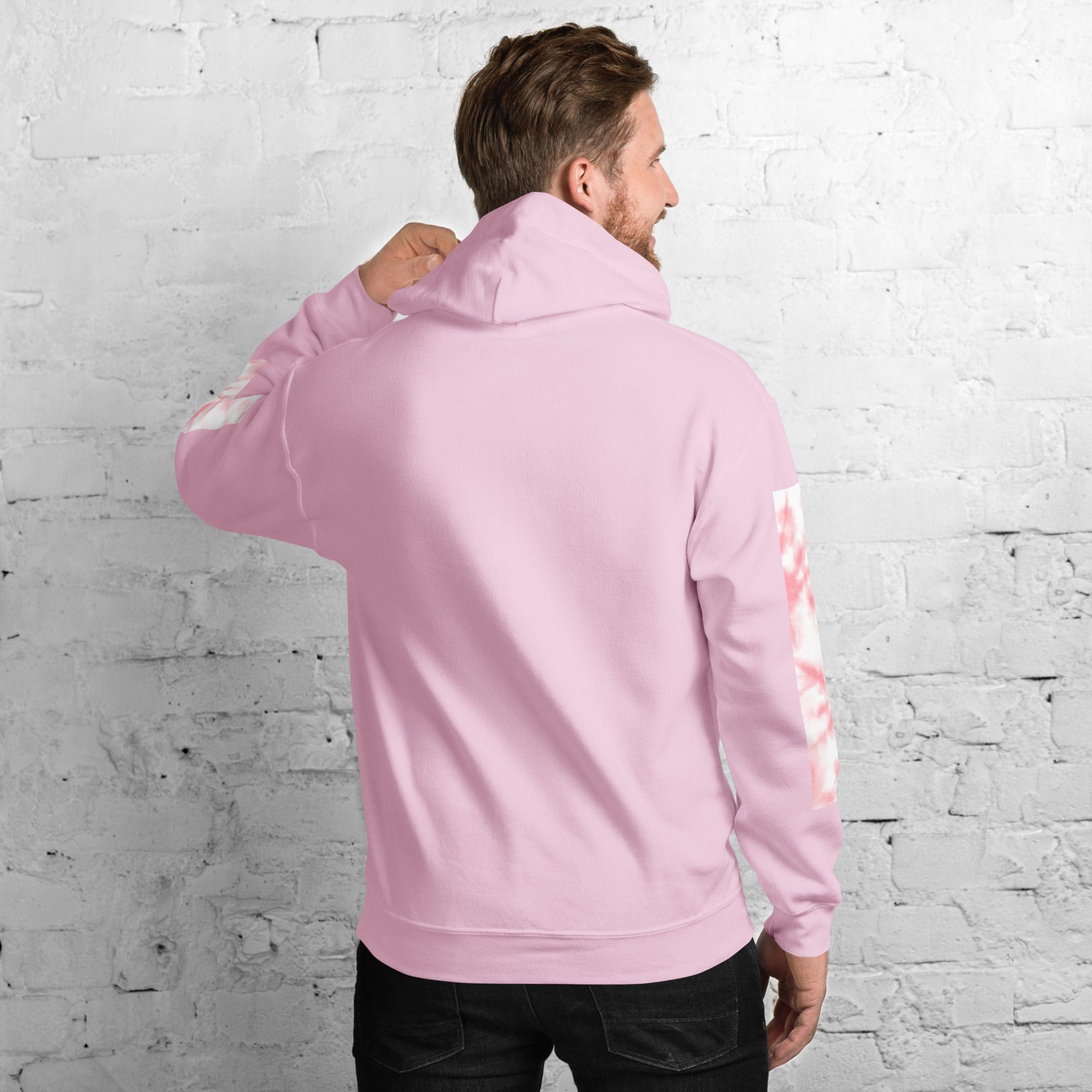 Man wearing pink hoodie facing wall.
