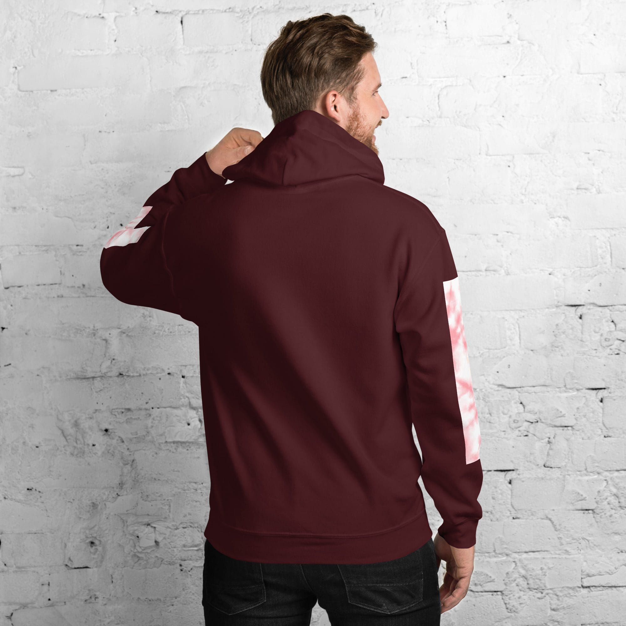 Man wearing maroon hoodie, white brick background.