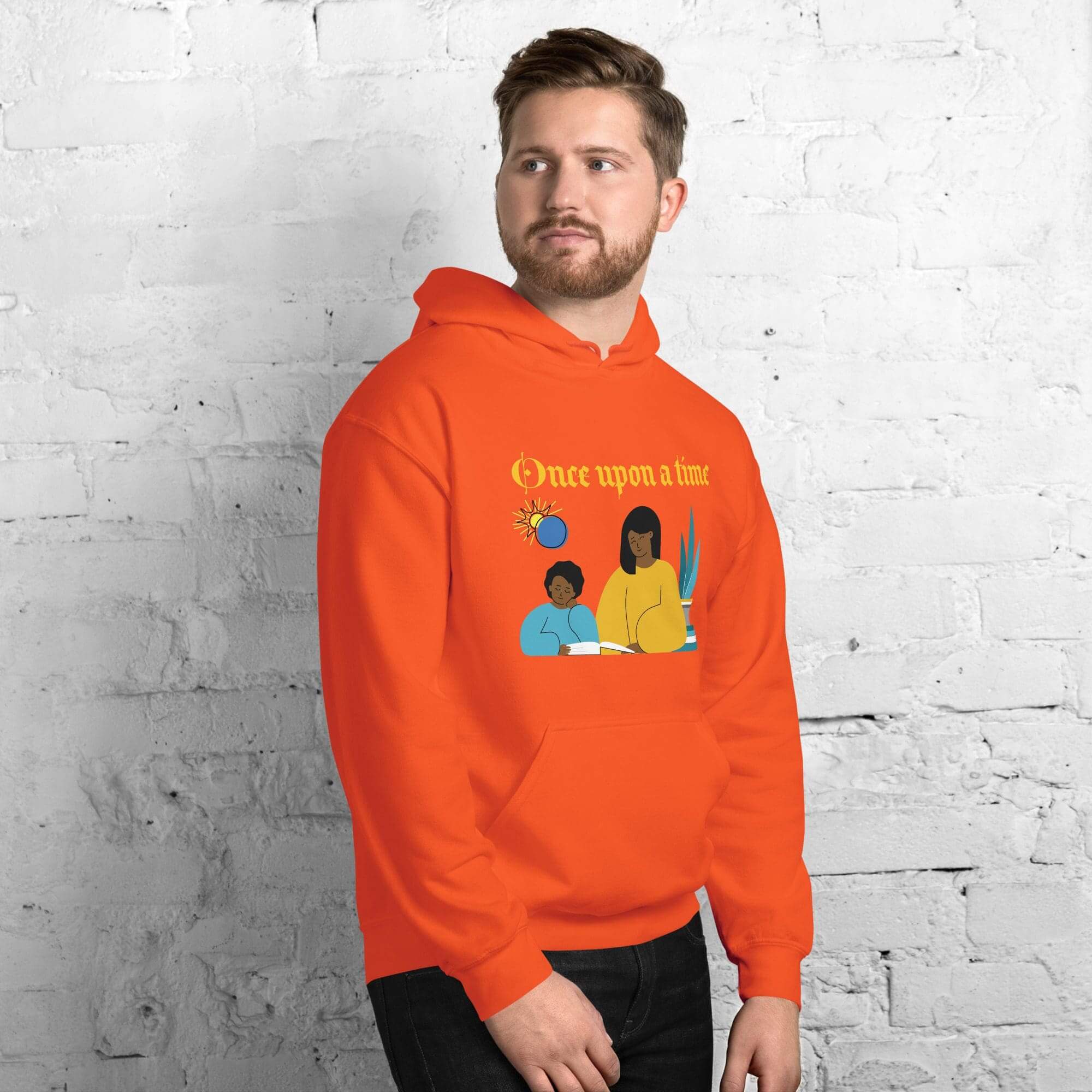 Man wearing orange hoodie against brick wall.