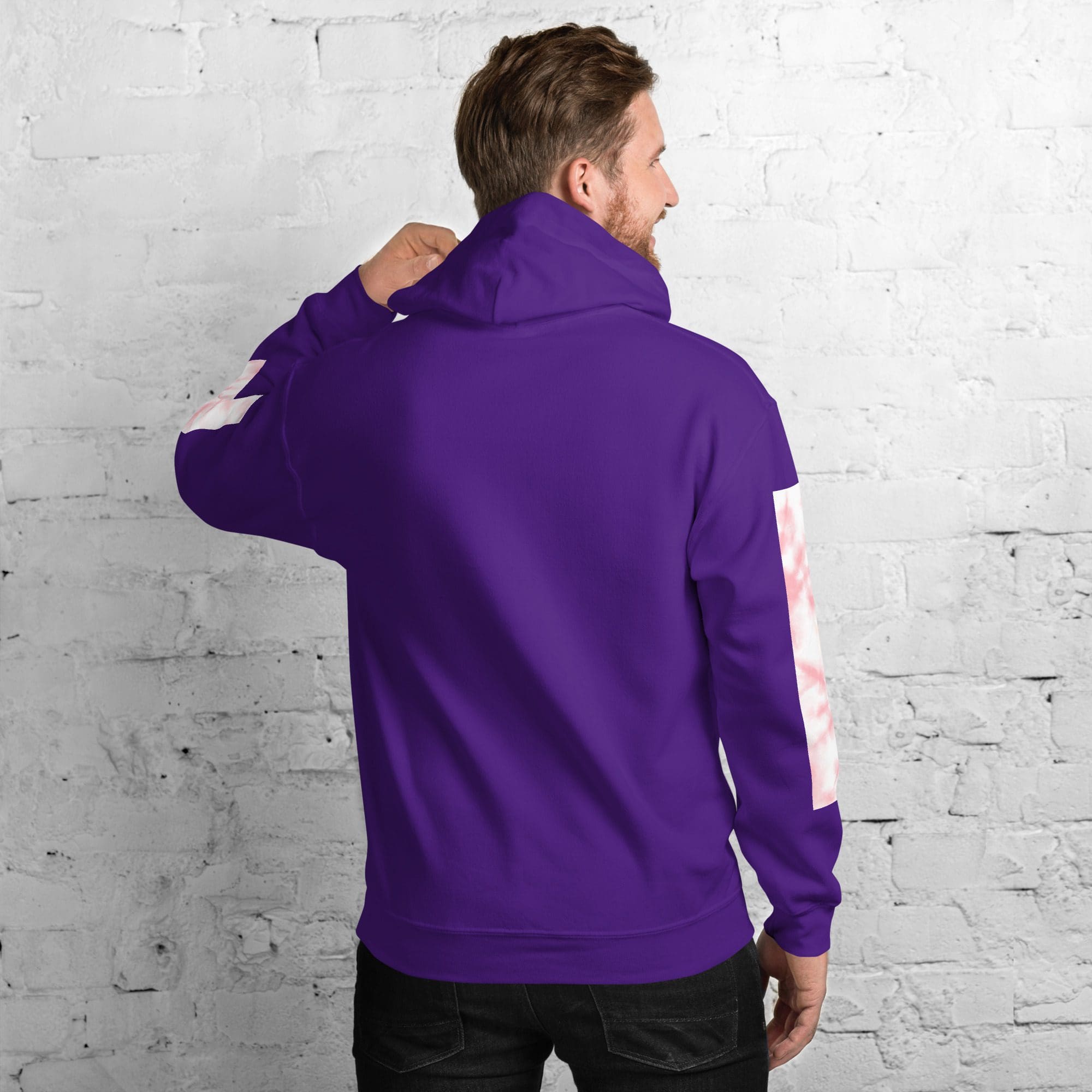 Man in purple hoodie against white brick wall