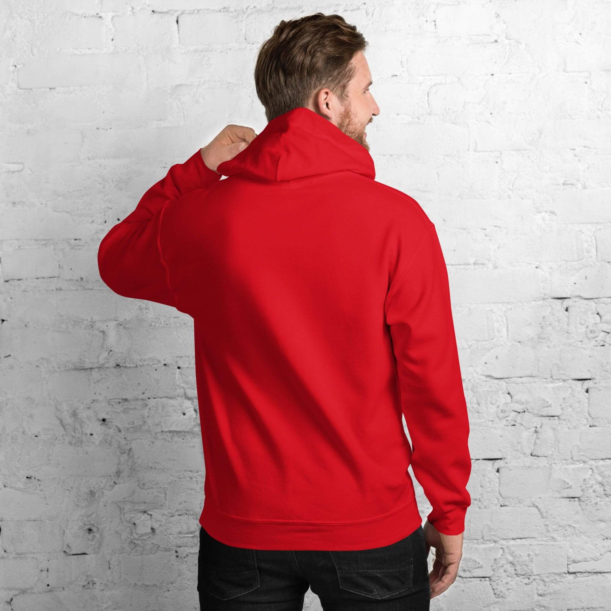 Man in red hoodie facing brick wall.