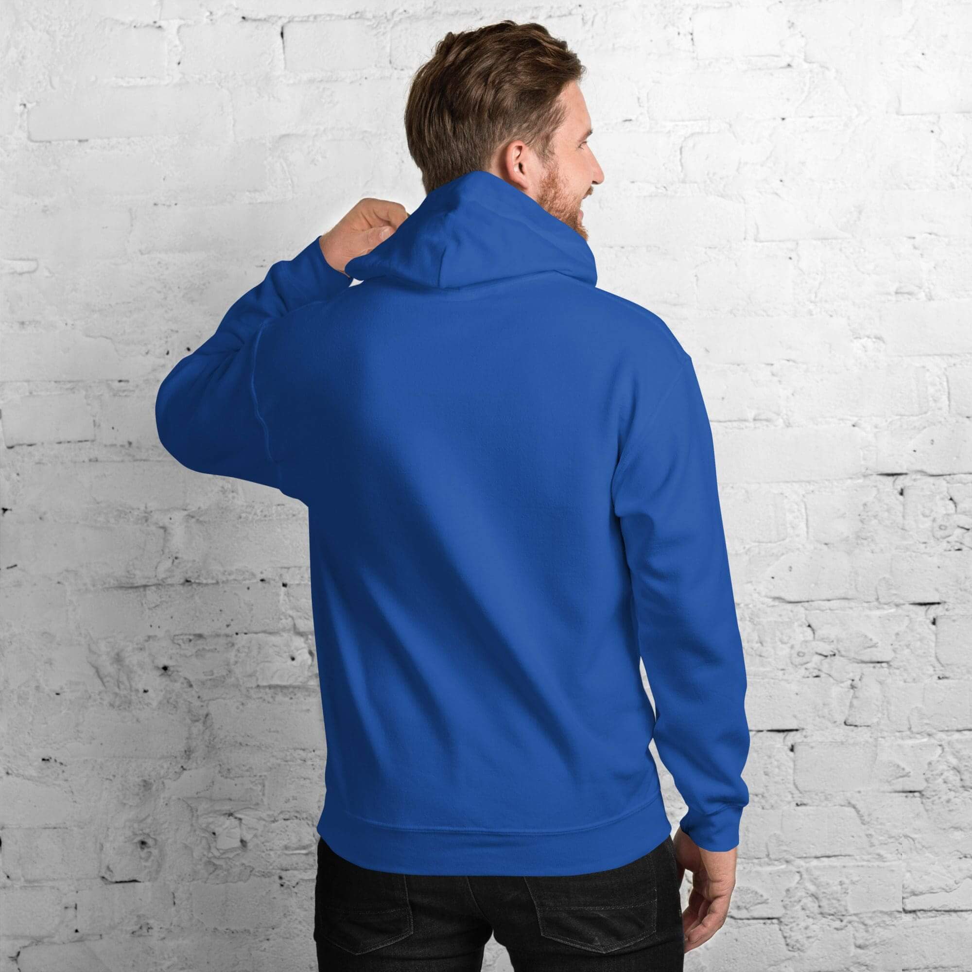 Man in blue hoodie facing white brick wall