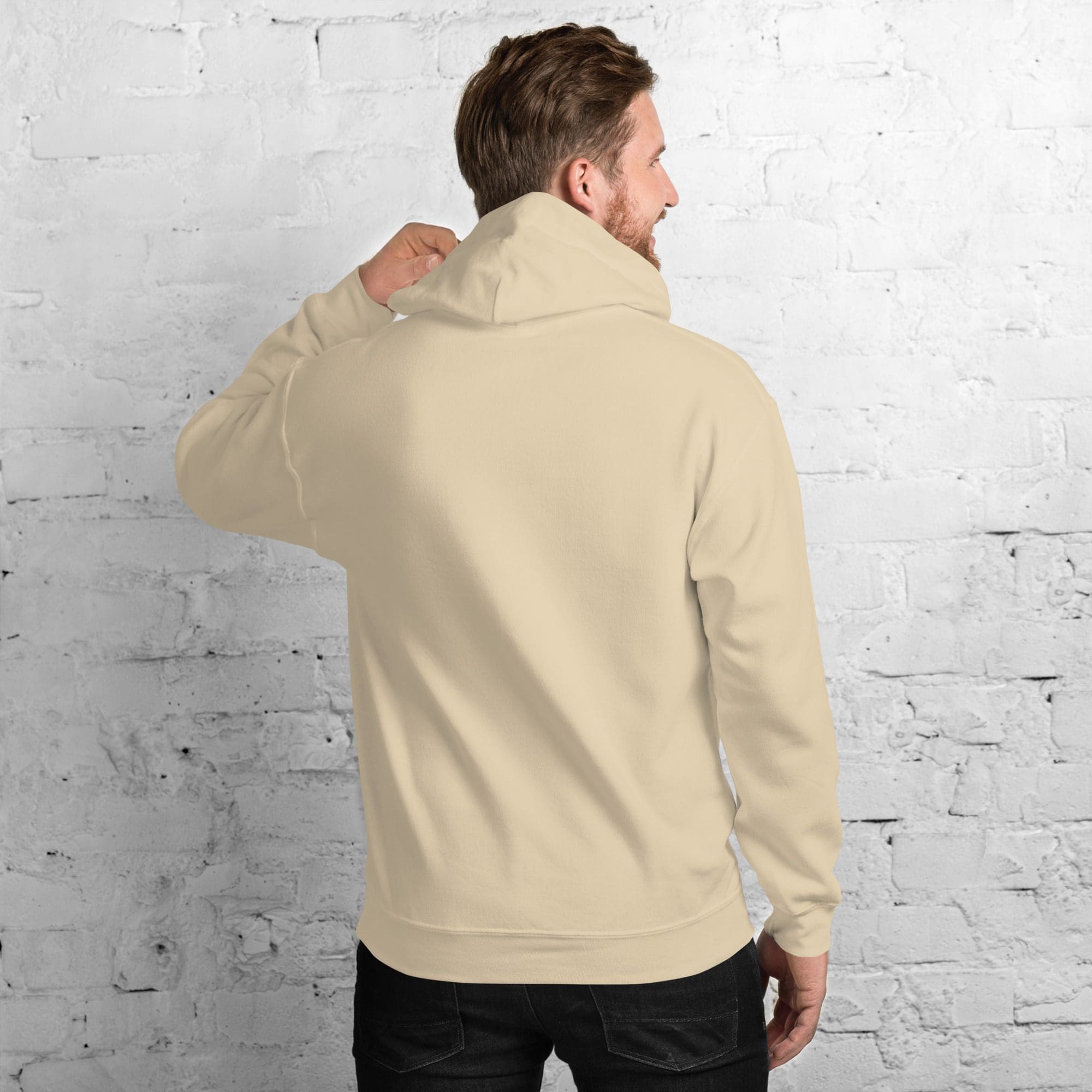 Man wearing beige hoodie facing wall.
