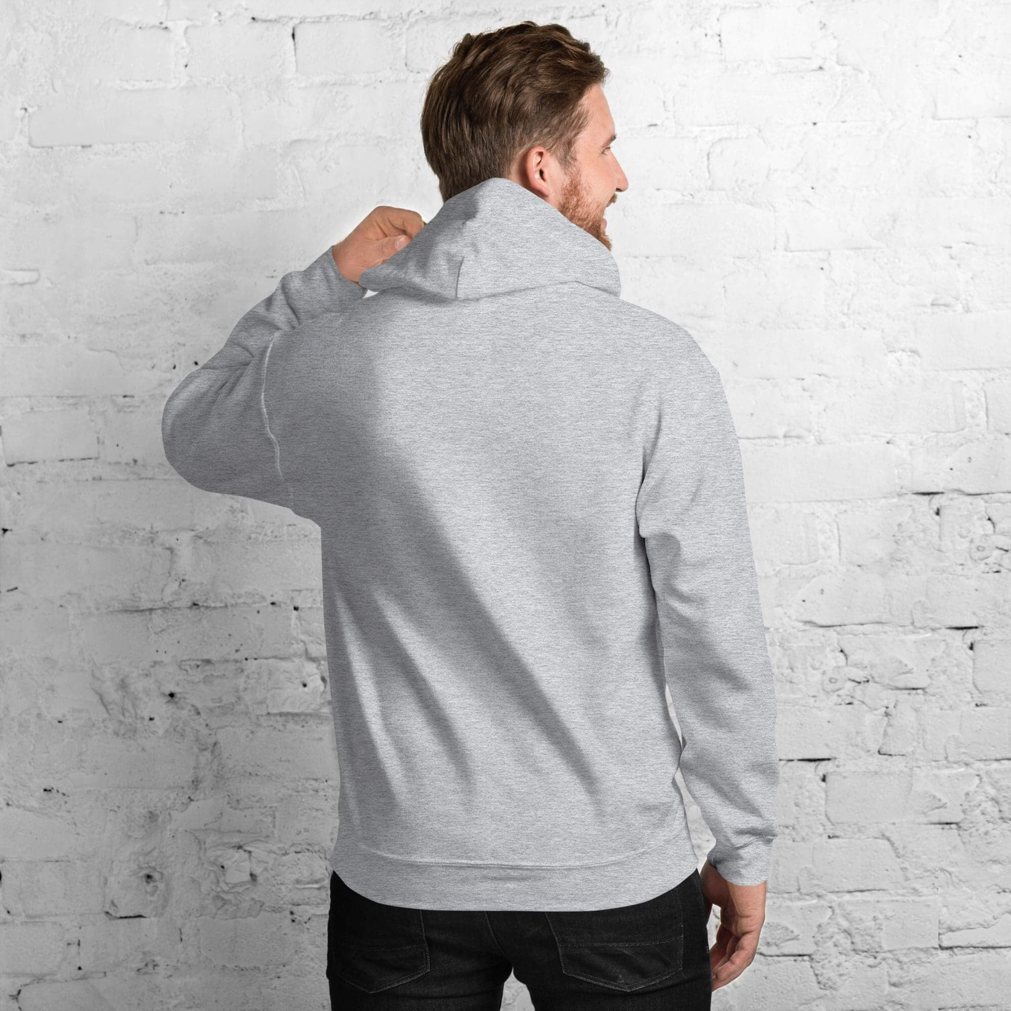 Man wearing gray hoodie facing wall.