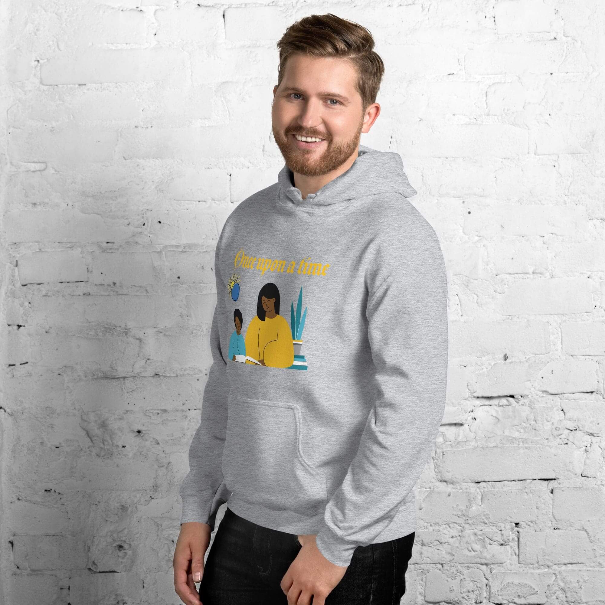 Man wearing gray hoodie, smiling against brick wall.