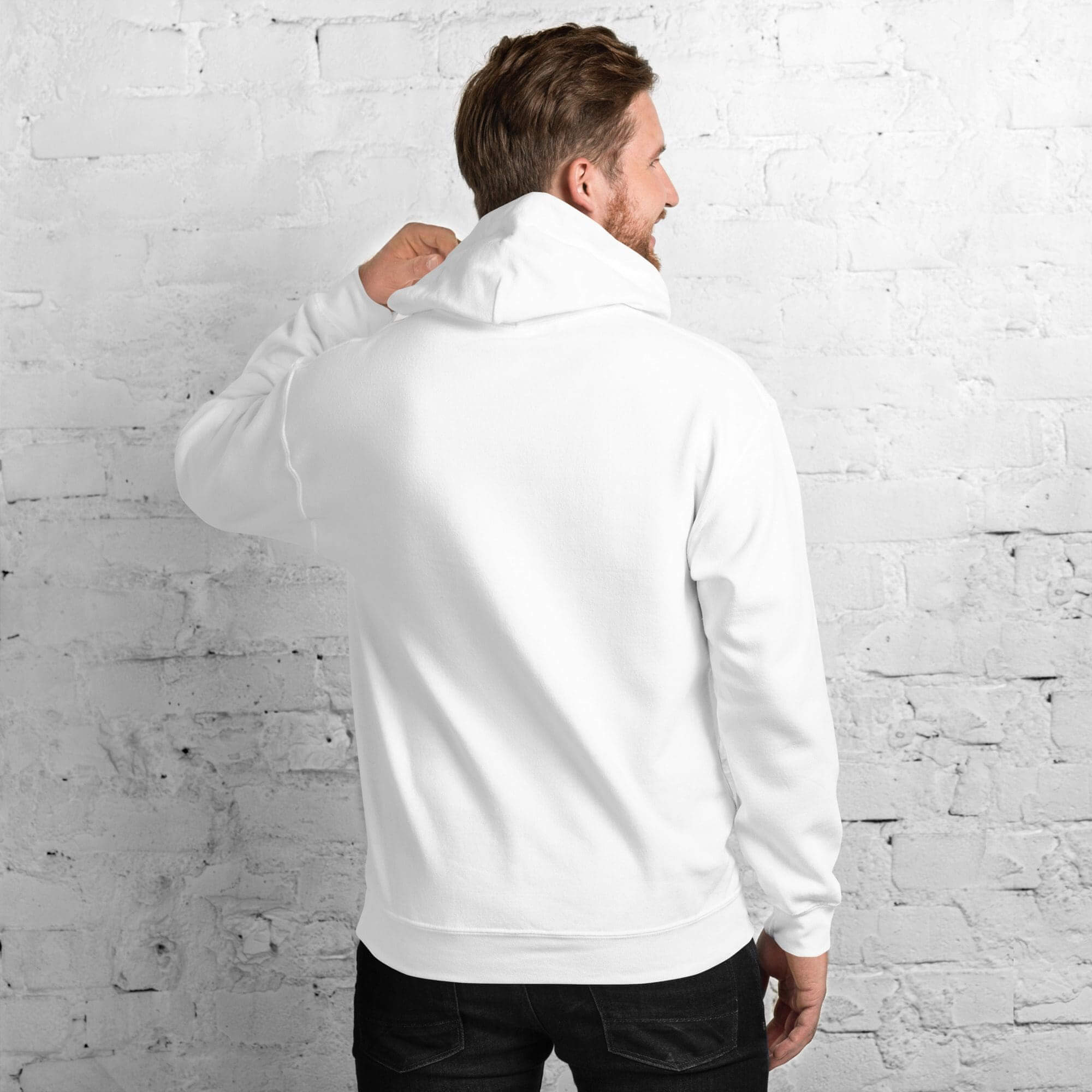Man wearing white hoodie, facing brick wall.