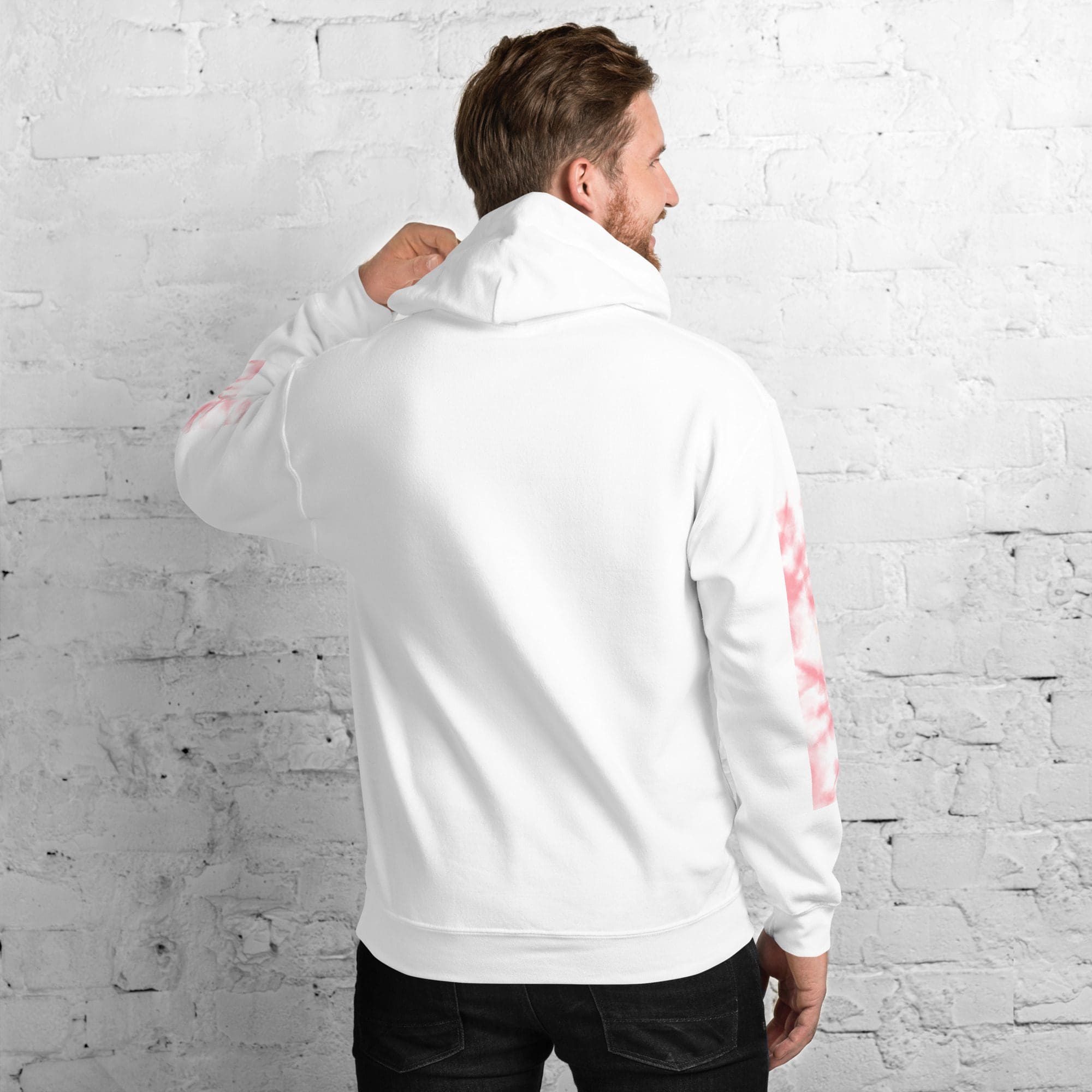 Man in white hoodie facing brick wall.