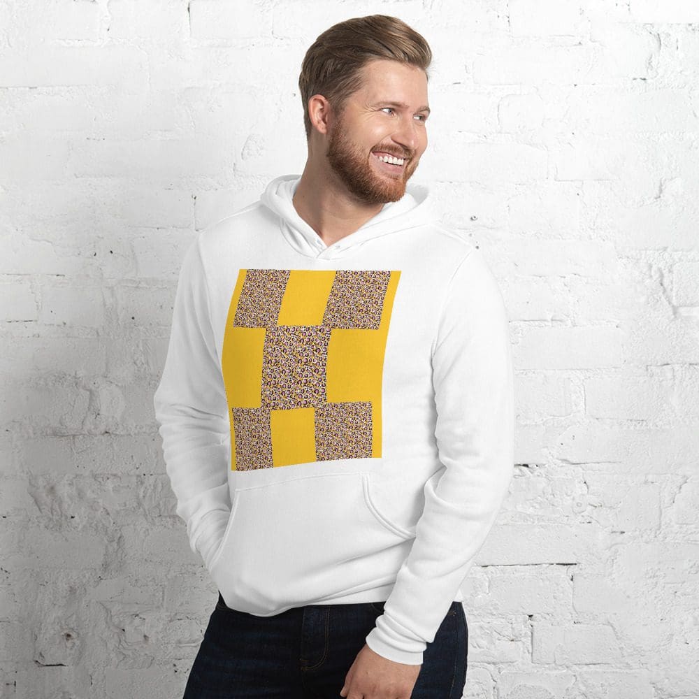 Man wearing patterned hoodie, smiling against wall.