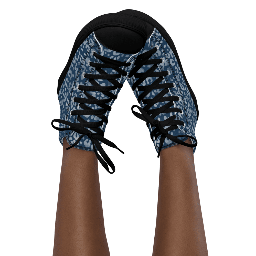 Legs wearing blue patterned sneakers, black background.