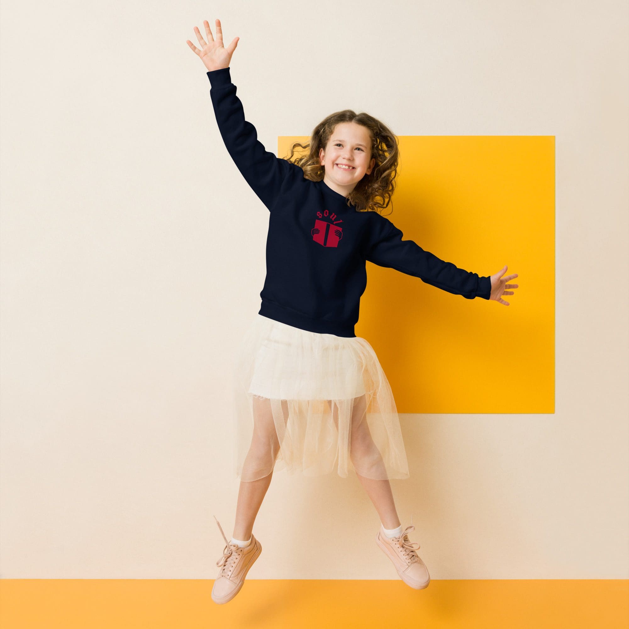 Girl jumping in tutu and sweatshirt.