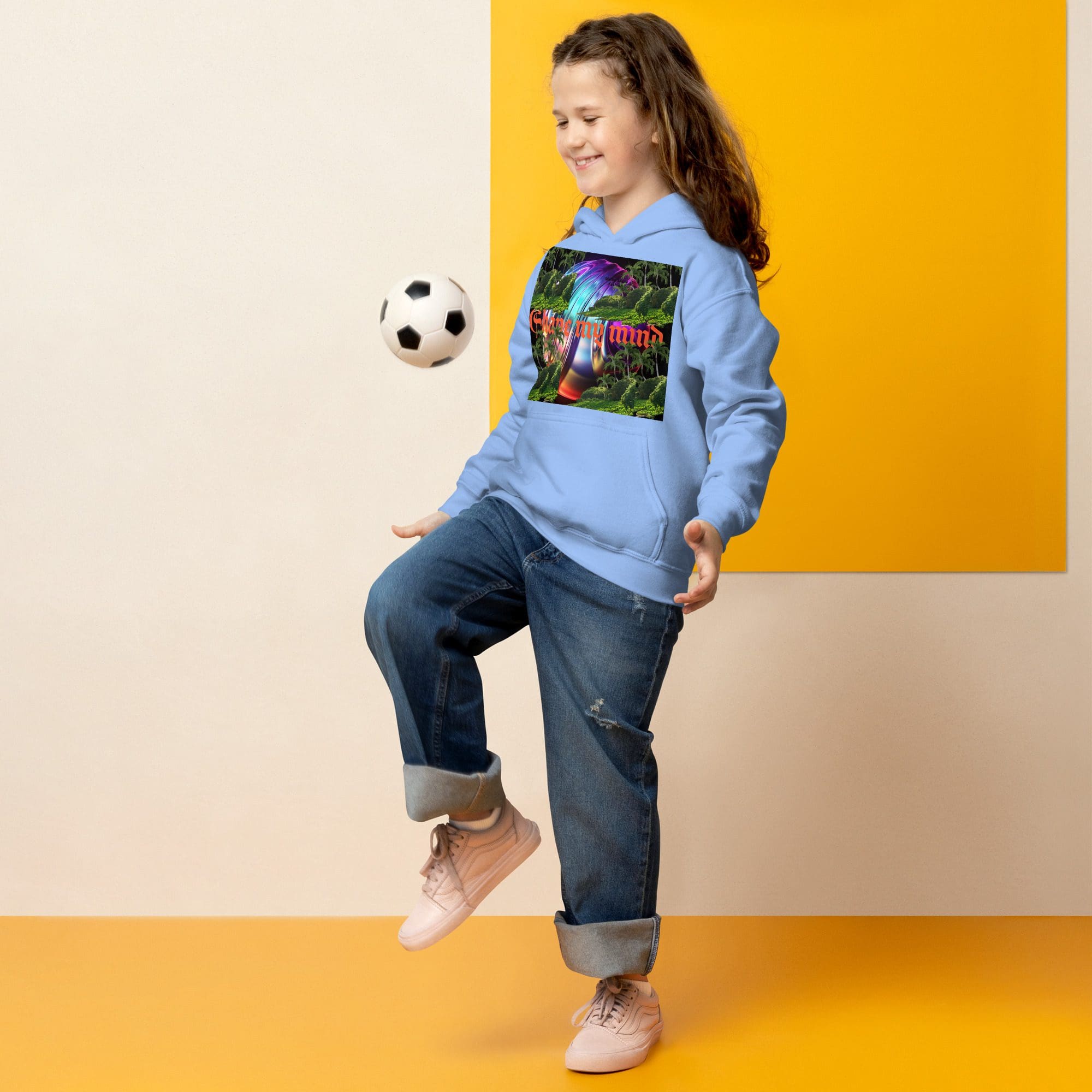 Girl juggling soccer ball in colorful hoodie.