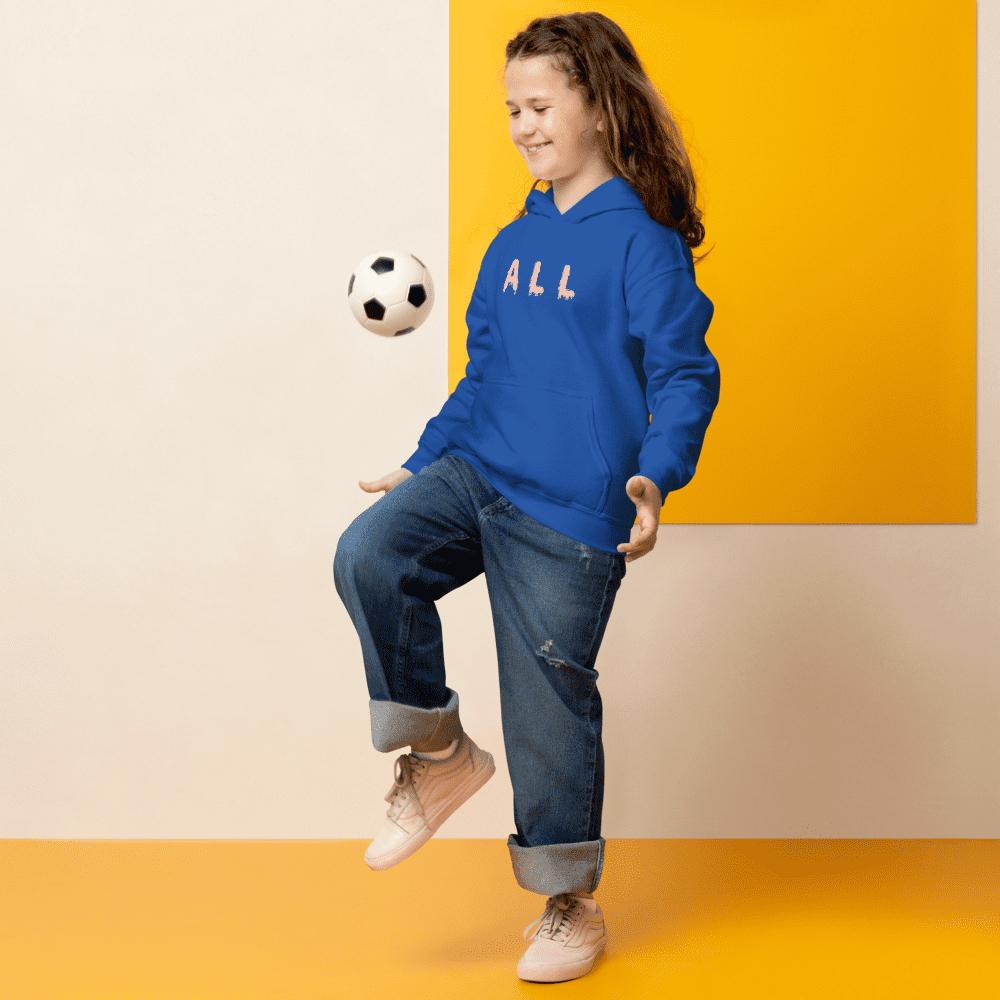 Smiling girl in blue hoodie kicking soccer ball