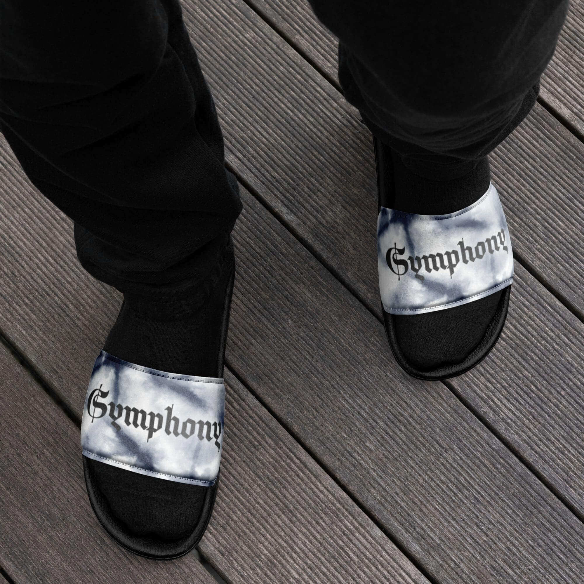 Person wearing "Symphony" slides on wooden deck.