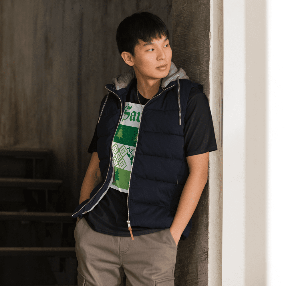 Young man leaning in stairwell wearing puffer vest